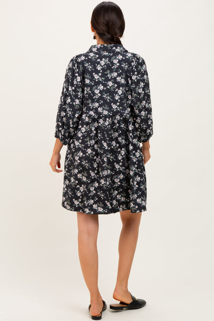 woman wearing a black floral print short dress with long sleeves and a loose fit, viewed from the back