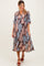 woman wearing a multicolored floral print maternity dress with three-quarter sleeves and a baby bump visible