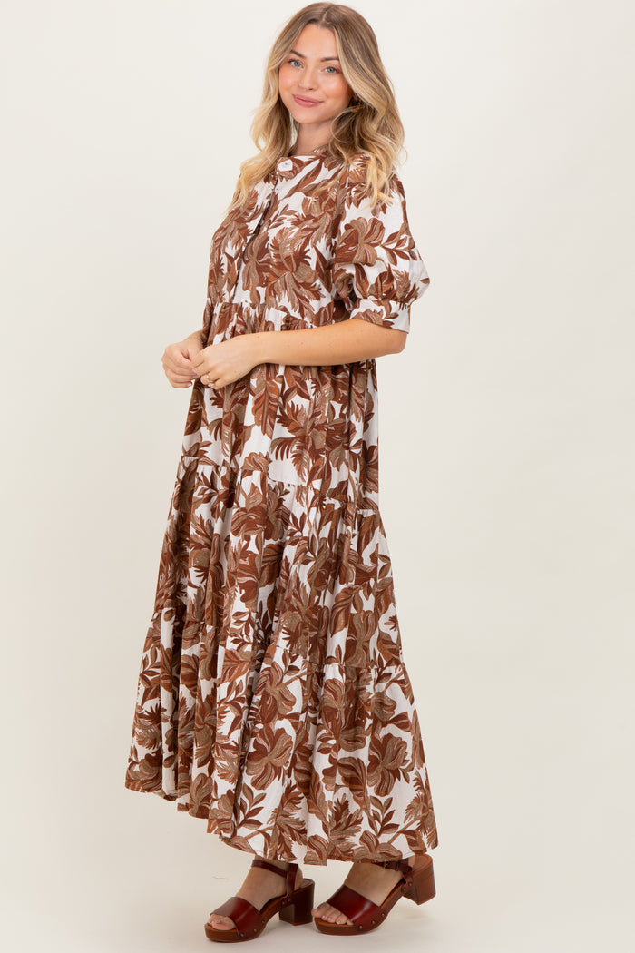 woman wearing a brown and white floral maxi dress with a tiered skirt and short sleeves