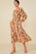 woman wearing a floral midi dress with long sleeves and pockets, styled with tan heeled sandals