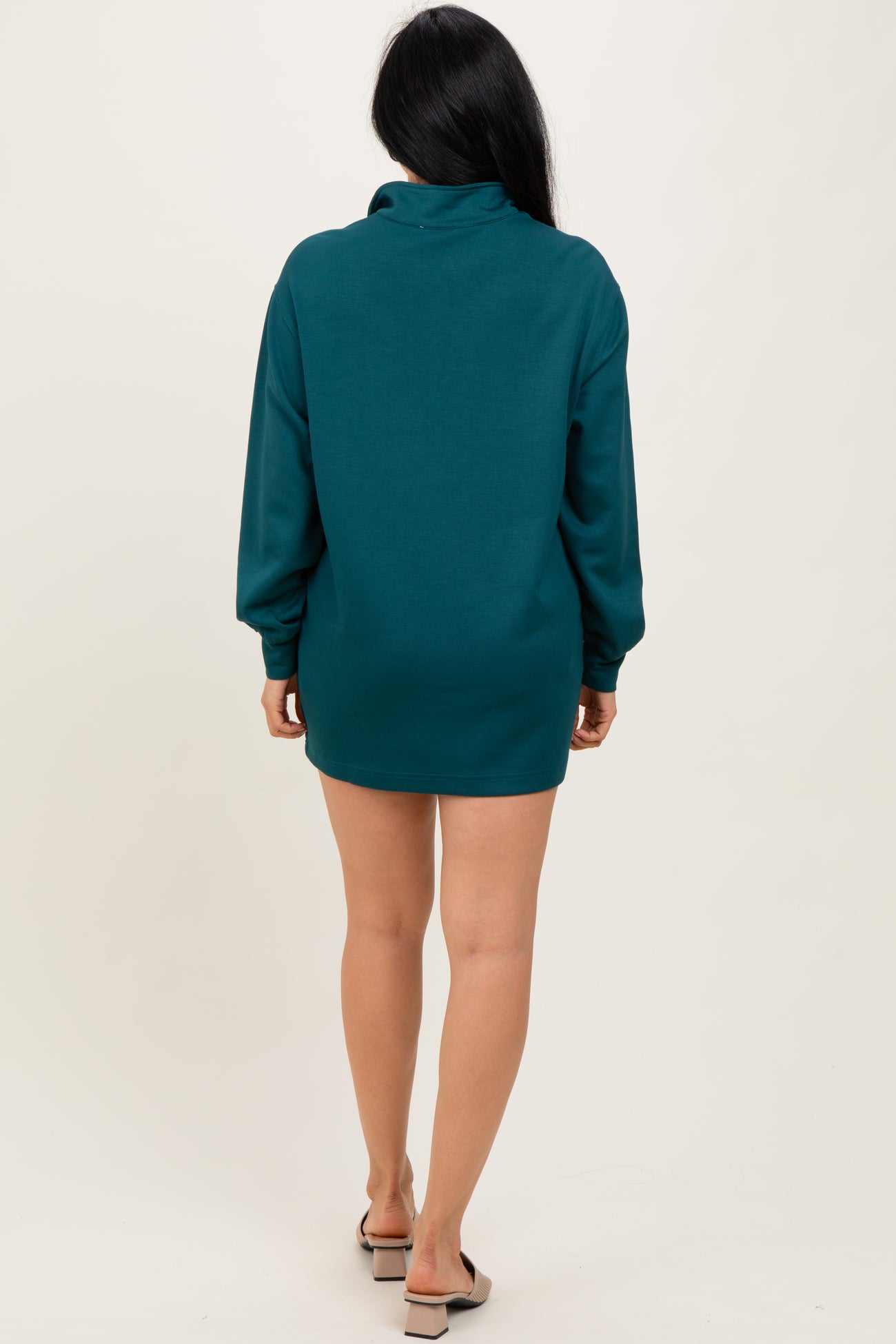 woman wearing a teal oversized sweater dress with long sleeves, shown from the back