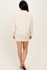 woman wearing a beige long sleeve oversized sweatshirt dress, standing with her back to the camera