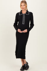 woman wearing a black ribbed maternity dress with a collar and button details, holding her baby bump