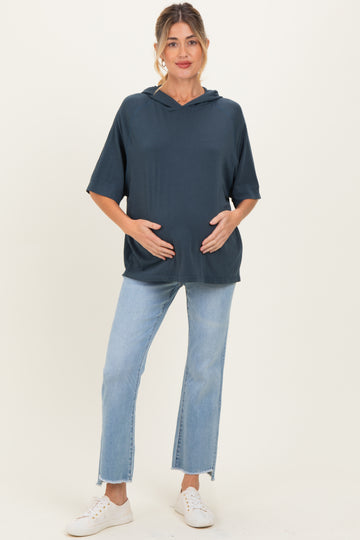woman wearing a dark blue short sleeve maternity hoodie and holding her baby bump with light wash jeans