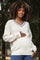 woman wearing a cream maternity sweater with navy blue accents and holding her baby bump