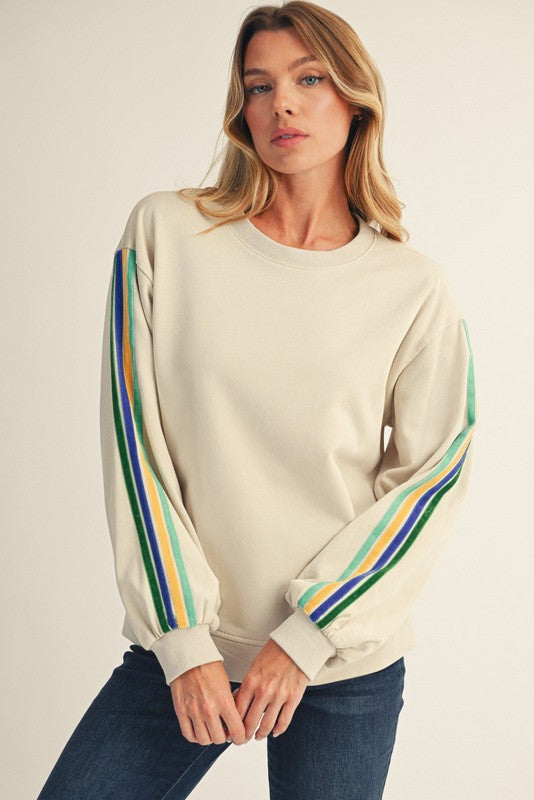 woman wearing a cream colored sweatshirt with striped balloon sleeves and paired with dark jeans