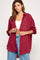 woman wearing a burgundy oversized button-up shirt and high-waisted jeans, posing with one hand on her waist