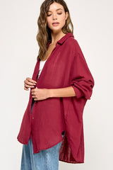 woman wearing a burgundy oversized button-up shirt styled with light blue wide-leg jeans