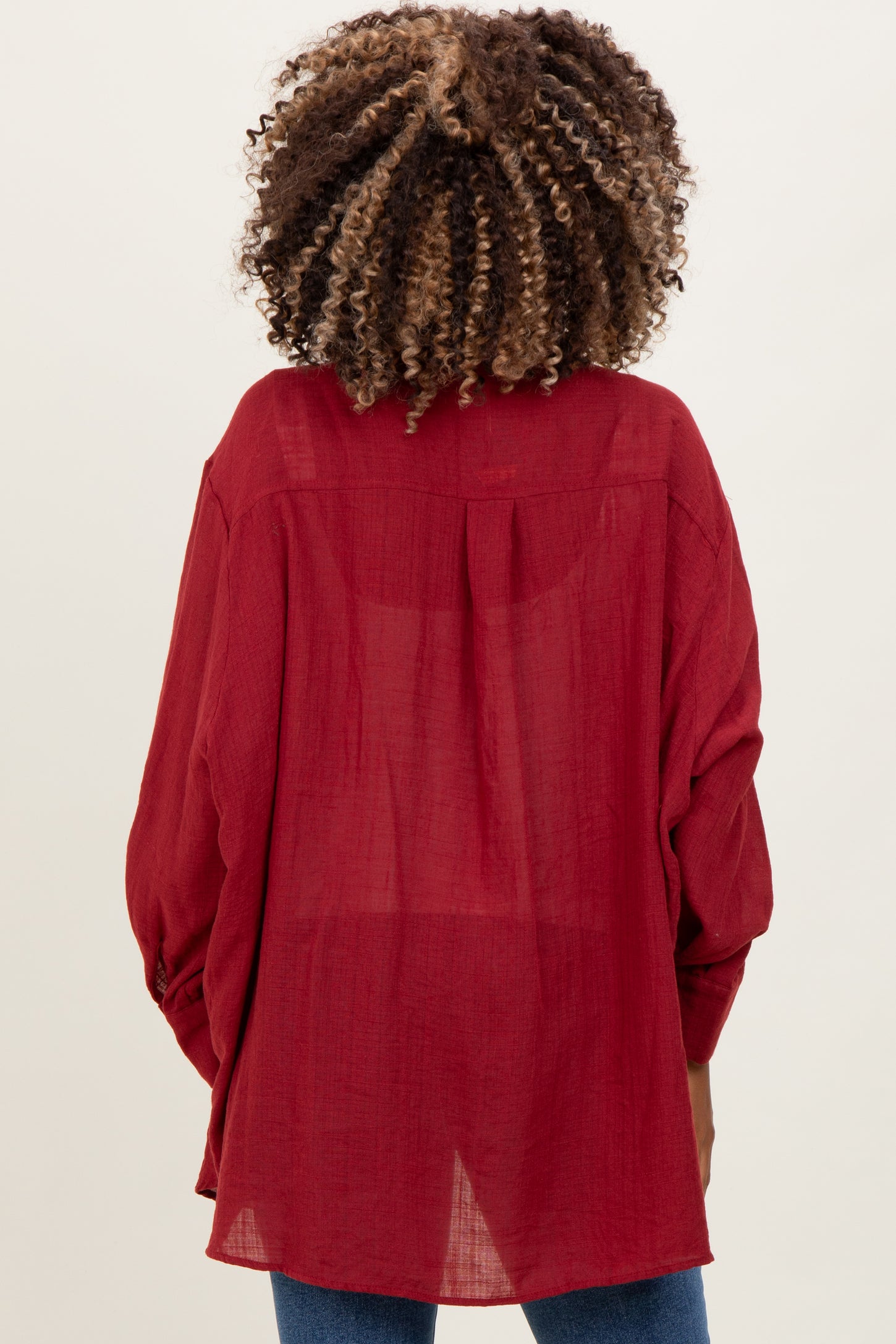 woman wearing a burgundy maternity blouse with long sleeves, seen from the back