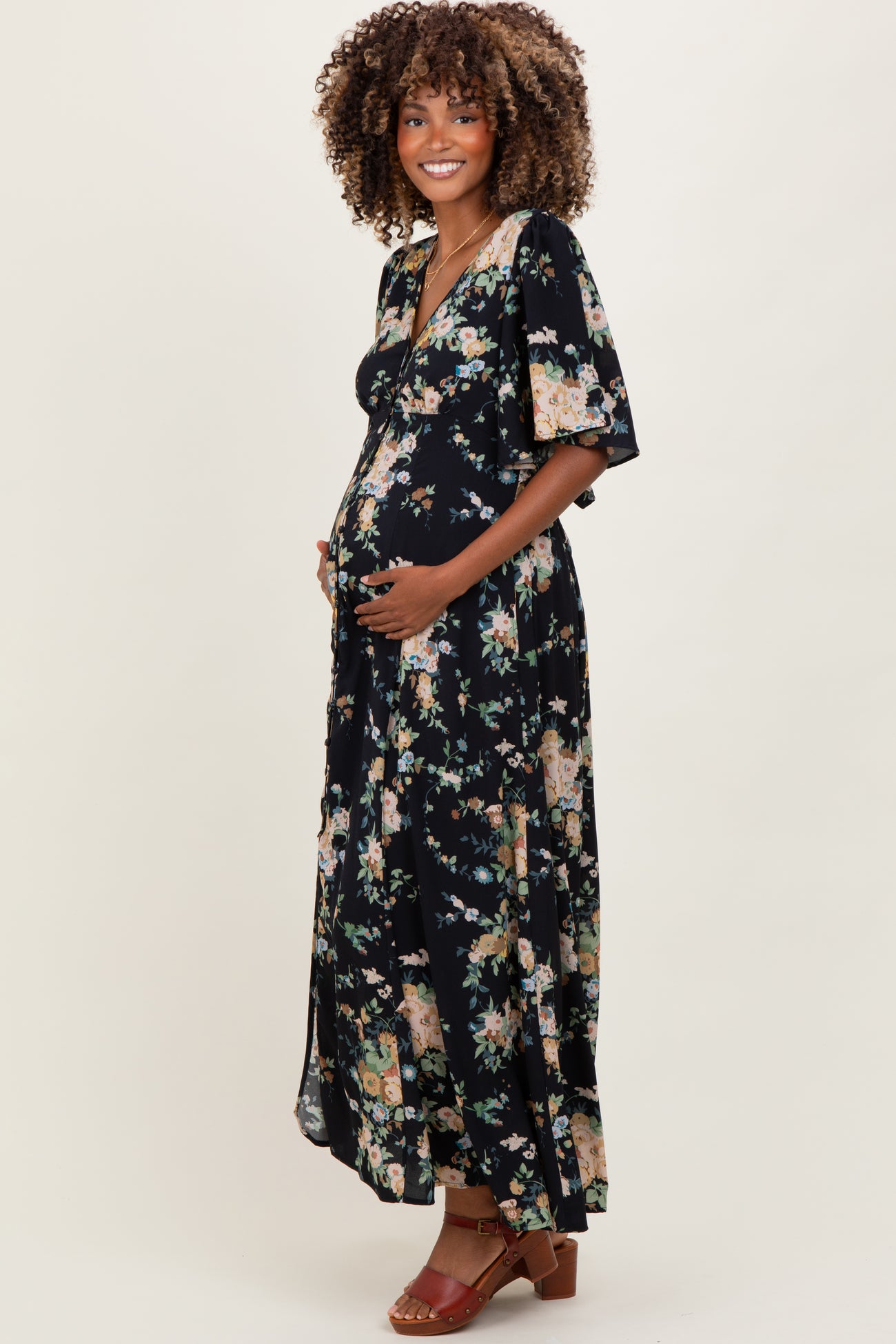 woman wearing a black floral maxi maternity dress and holding her baby bump