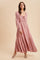 woman wearing a blush pink long sleeve maxi dress with a tie front and tiered skirt
