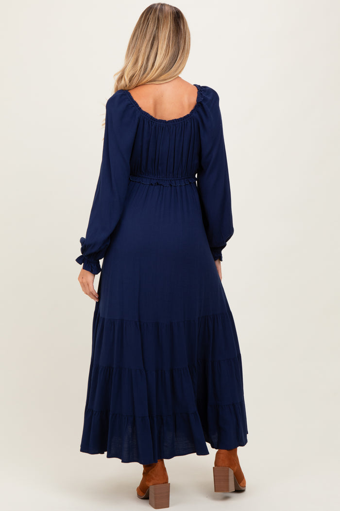 woman wearing a navy blue long sleeve maternity dress with a tiered skirt and elastic waist, showing a baby bump from behind