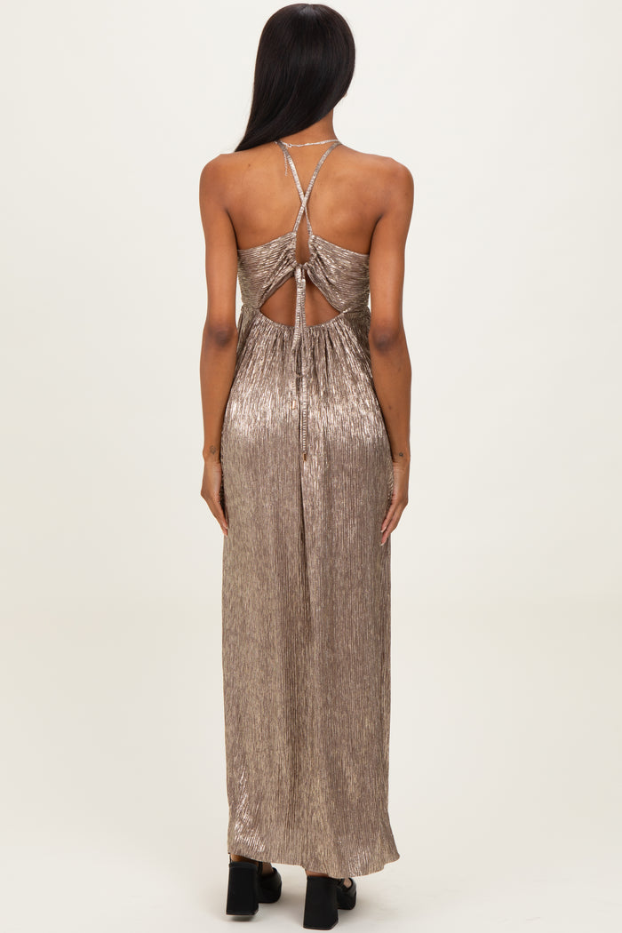 woman wearing a metallic gold backless maxi dress with crisscross straps and a flowing silhouette