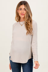 woman wearing a beige long sleeve maternity top with side slits and a visible baby bump