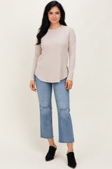 woman wearing a beige long sleeve ribbed top with a curved hem and light blue frayed hem jeans