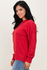 woman wearing a red long sleeve sweater with a relaxed fit and side slits, smiling while standing sideways