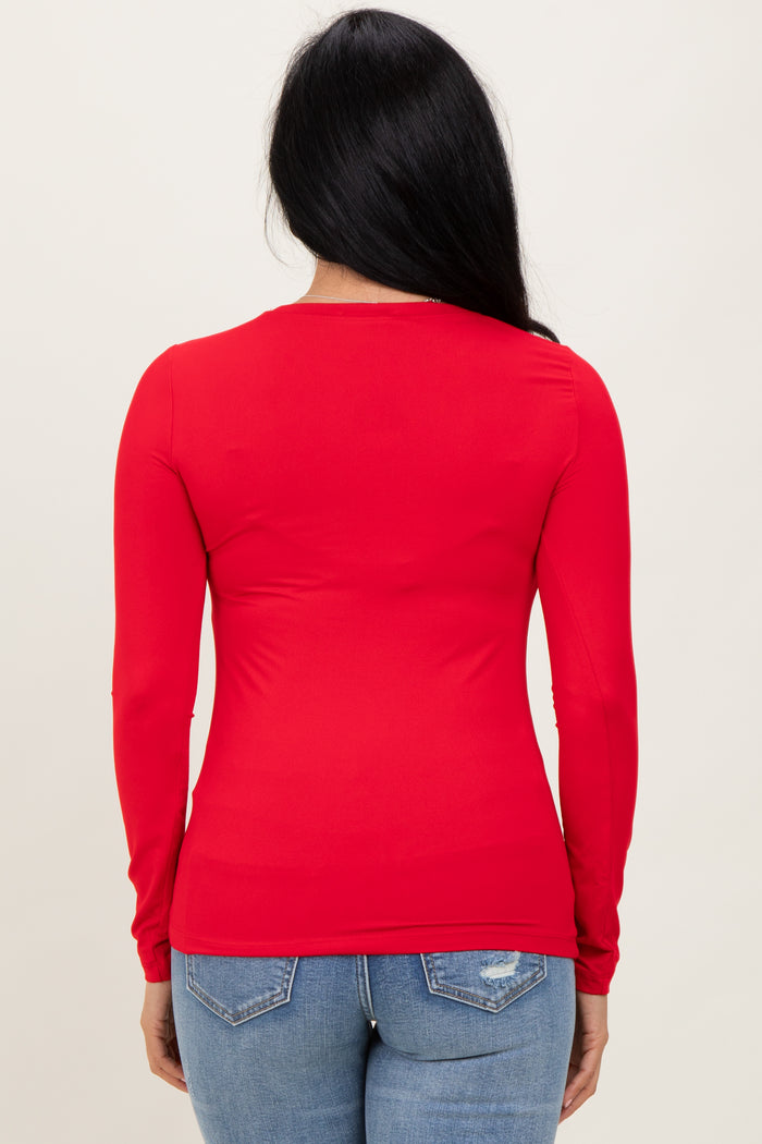 woman wearing a fitted red long sleeve top, seen from the back, paired with light blue jeans