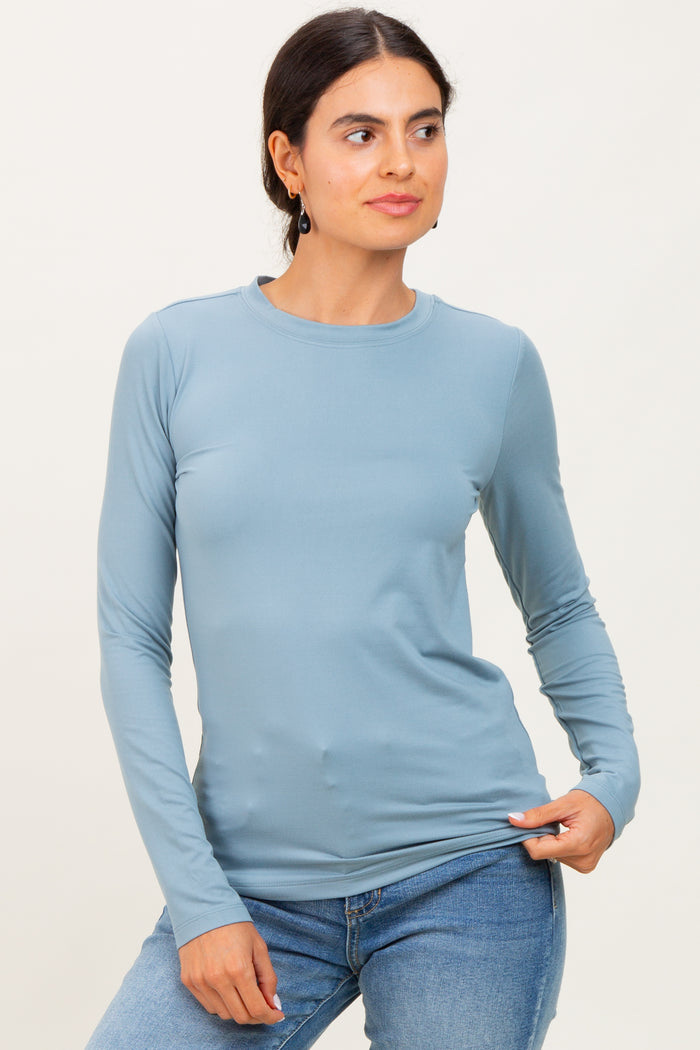 woman wearing a light blue long sleeve top with a crew neckline and fitted silhouette