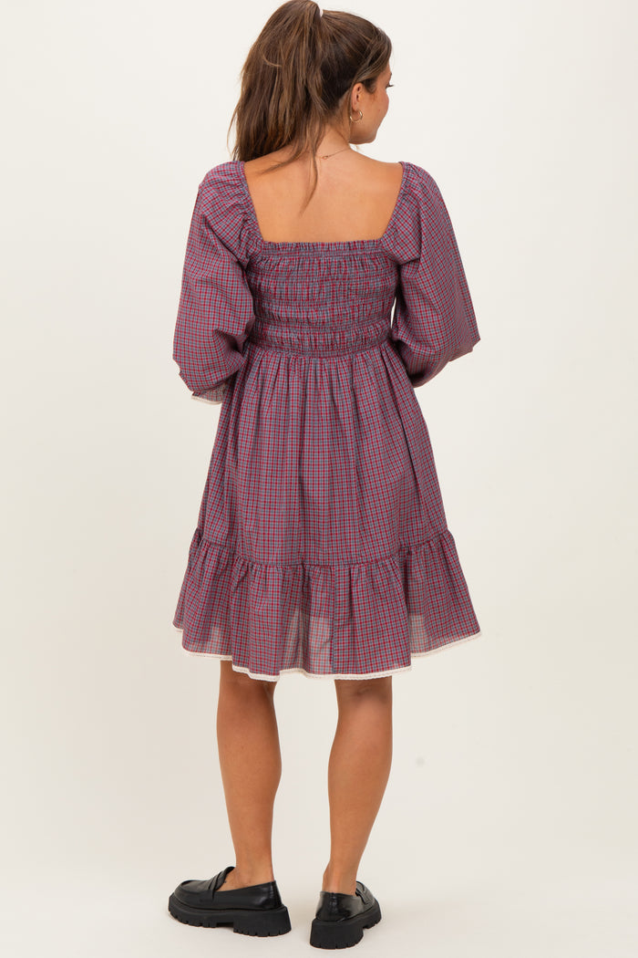 woman wearing a purple checkered maternity dress with puffed sleeves and a tiered skirt, showing a baby bump
