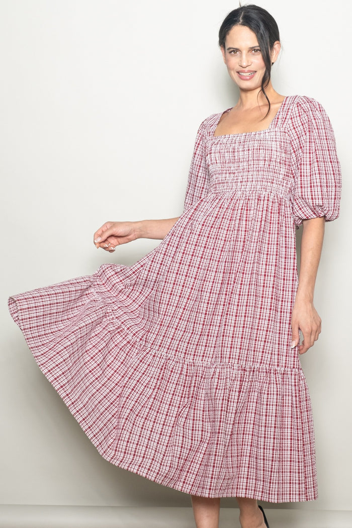 woman wearing a red and white checked puff sleeve midi dress with a smocked bodice and tiered hem