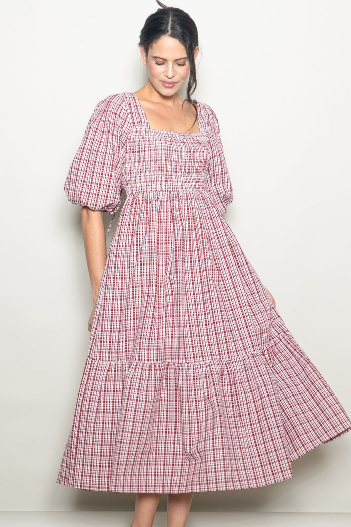 woman wearing a red and white checkered puff sleeve midi dress with a smocked bodice and tiered skirt