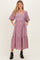 woman wearing a pink and white gingham maternity midi dress with puff sleeves and pockets, showcasing her baby bump