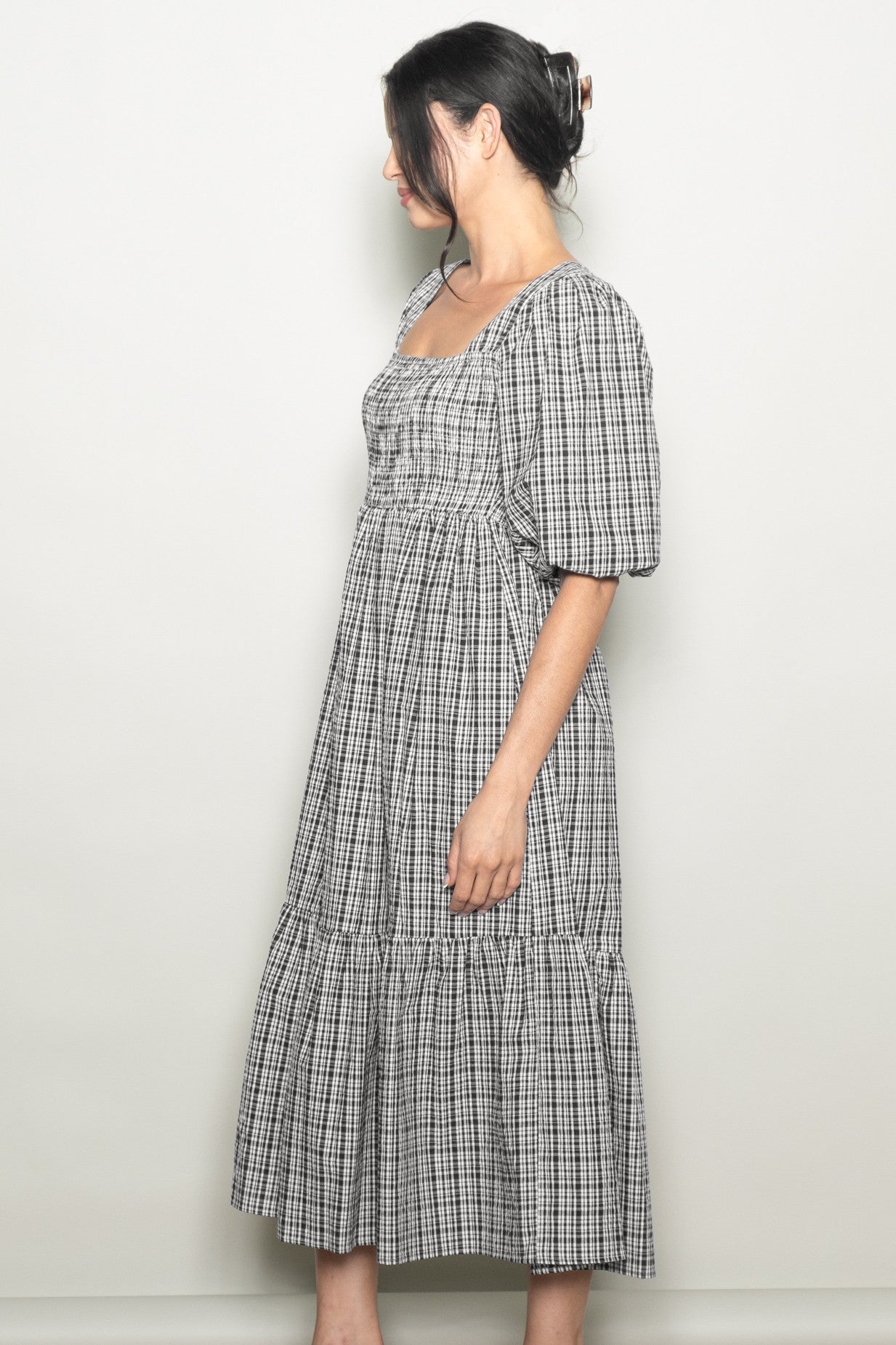 woman wearing a black and white plaid midi dress with puff sleeves and a tiered skirt