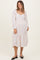 woman wearing a white maternity dress with red polka dots and a tiered hem, displaying her baby bump