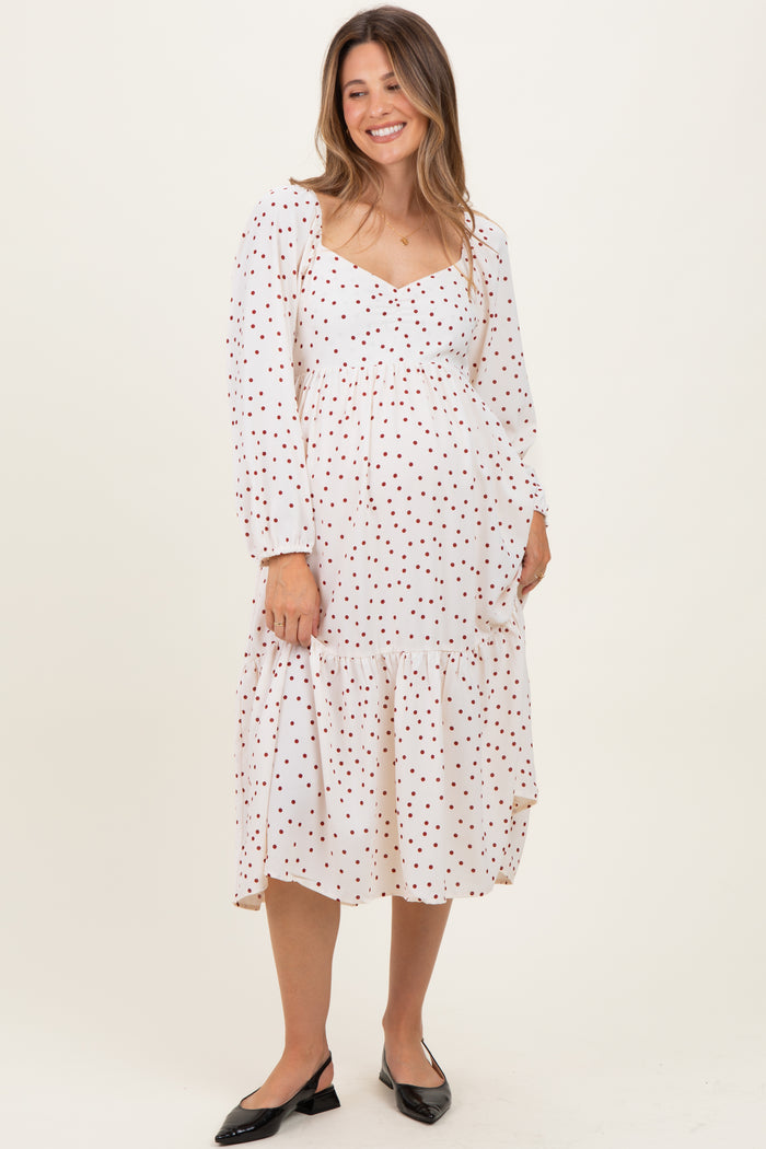 woman wearing a white maternity dress with red polka dots and a tiered hem, displaying her baby bump