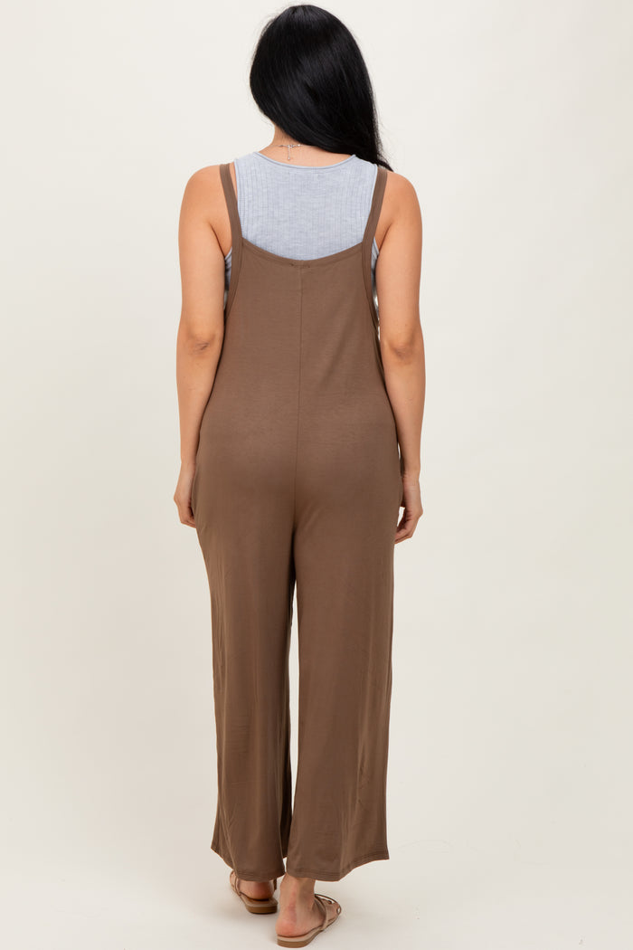 woman wearing a brown backless jumpsuit with a loose fit and wide legs, showing a gray tank top underneath
