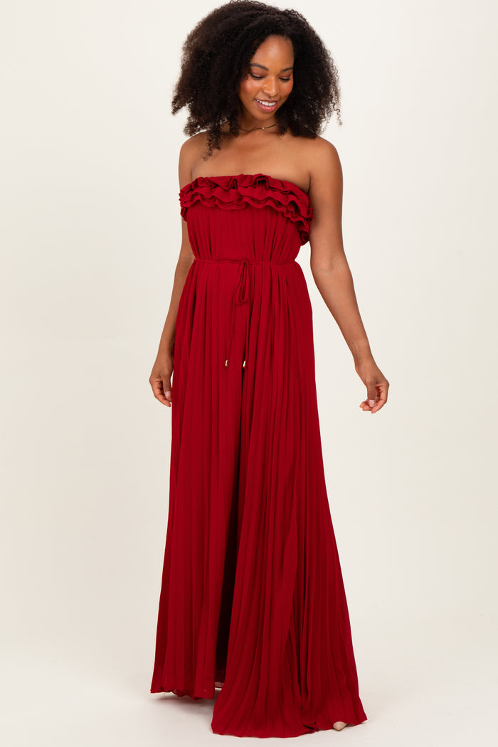 woman wearing a flowy red strapless maxi dress with ruffle details and a cinched waist.