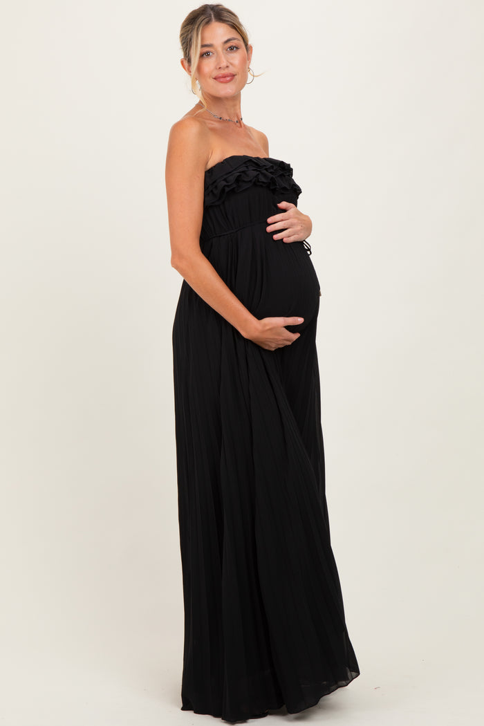 woman wearing a black strapless maternity maxi dress with ruffle detailing and holding her baby bump