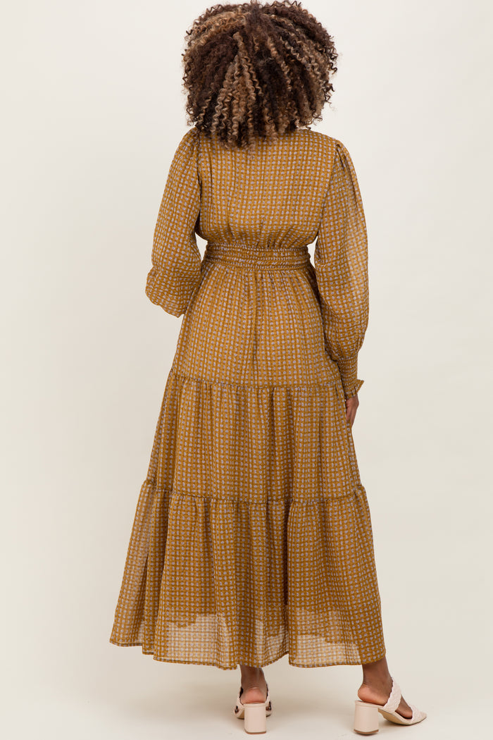 woman wearing a mustard yellow tiered maternity dress with long sleeves and a fitted waist from the back