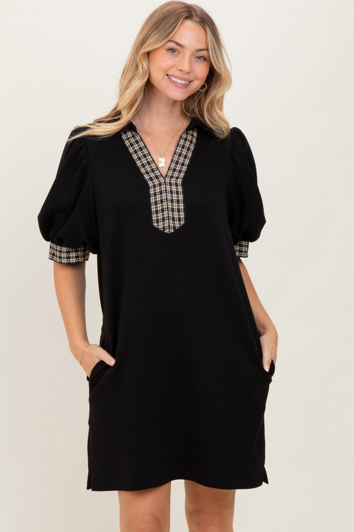 woman wearing a black puff sleeve dress with a plaid neckline and side pockets
