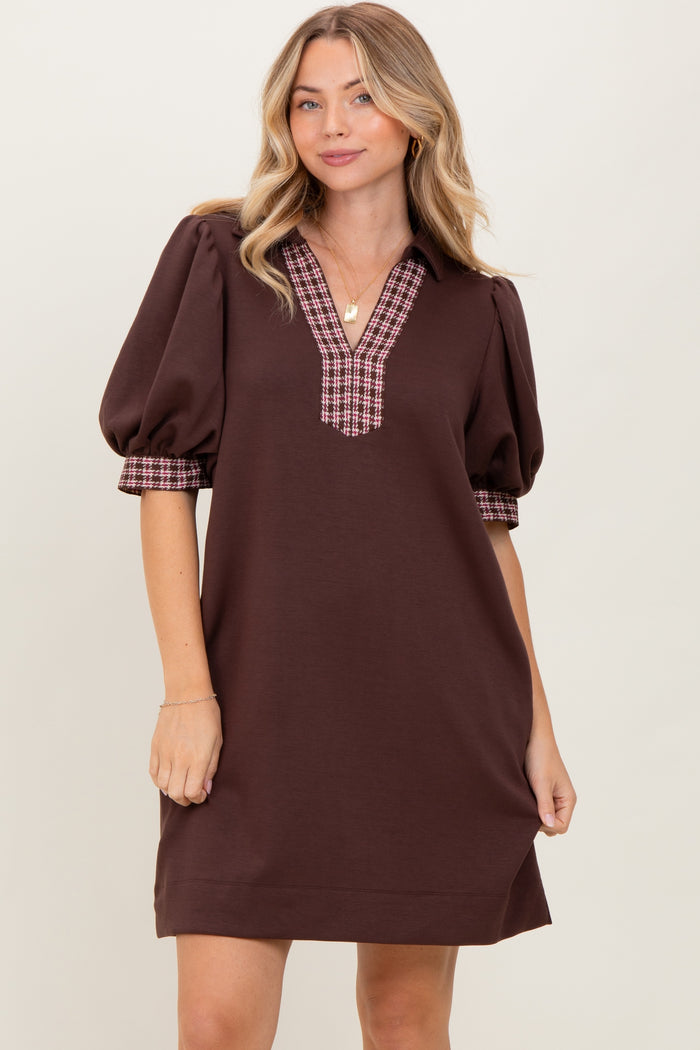 woman wearing a brown short sleeve dress with puff sleeves and plaid detail on the cuffs