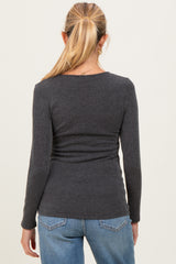 woman wearing a dark gray ribbed long sleeve maternity top with a fitted silhouette and styled with high-waisted jeans