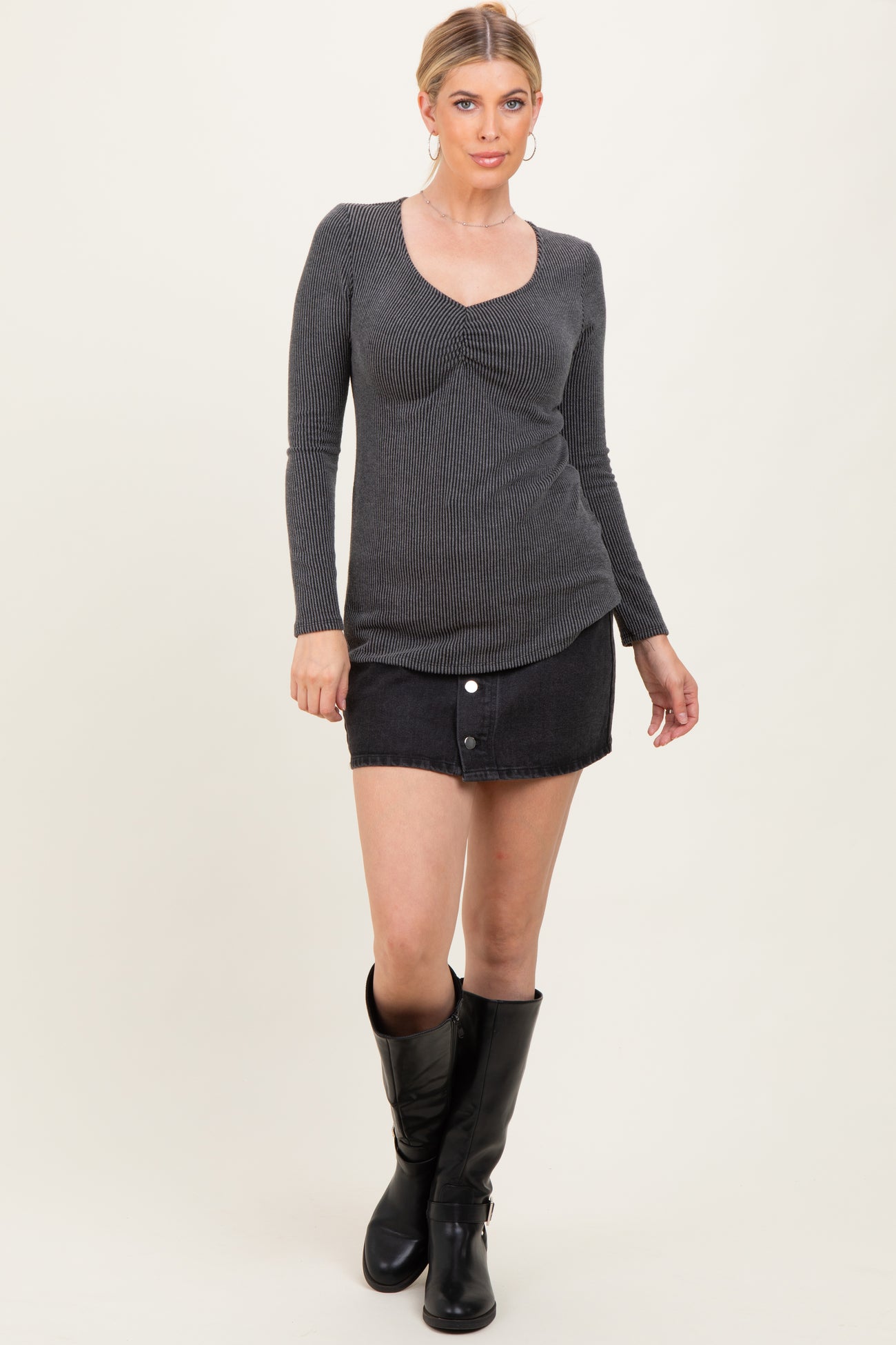 woman wearing a gray ribbed long sleeve top and a black denim mini skirt, paired with knee-high black boots