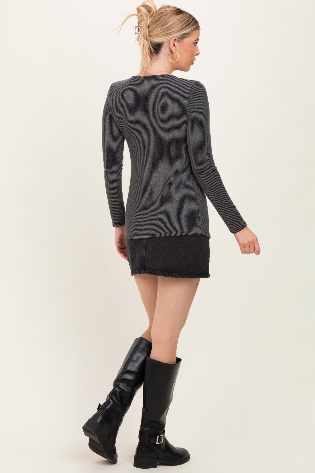 woman wearing a dark gray ribbed long sleeve top, paired with a black denim skirt and tall black boots