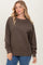 woman wearing a brown oversized sweatshirt with long sleeves and ribbed cuffs paired with blue jeans