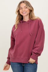 woman wearing a burgundy hooded sweatshirt with a relaxed fit and long sleeves, smiling at the camera