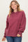woman wearing a burgundy hooded sweatshirt with a relaxed fit and long sleeves, smiling at the camera