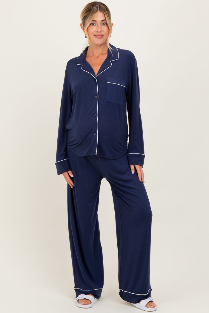 woman wearing a navy blue long sleeve maternity pajama set with white piping details and loose-fitting trousers