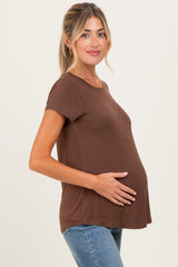 woman wearing a brown maternity t-shirt with a visible baby bump and holding her stomach