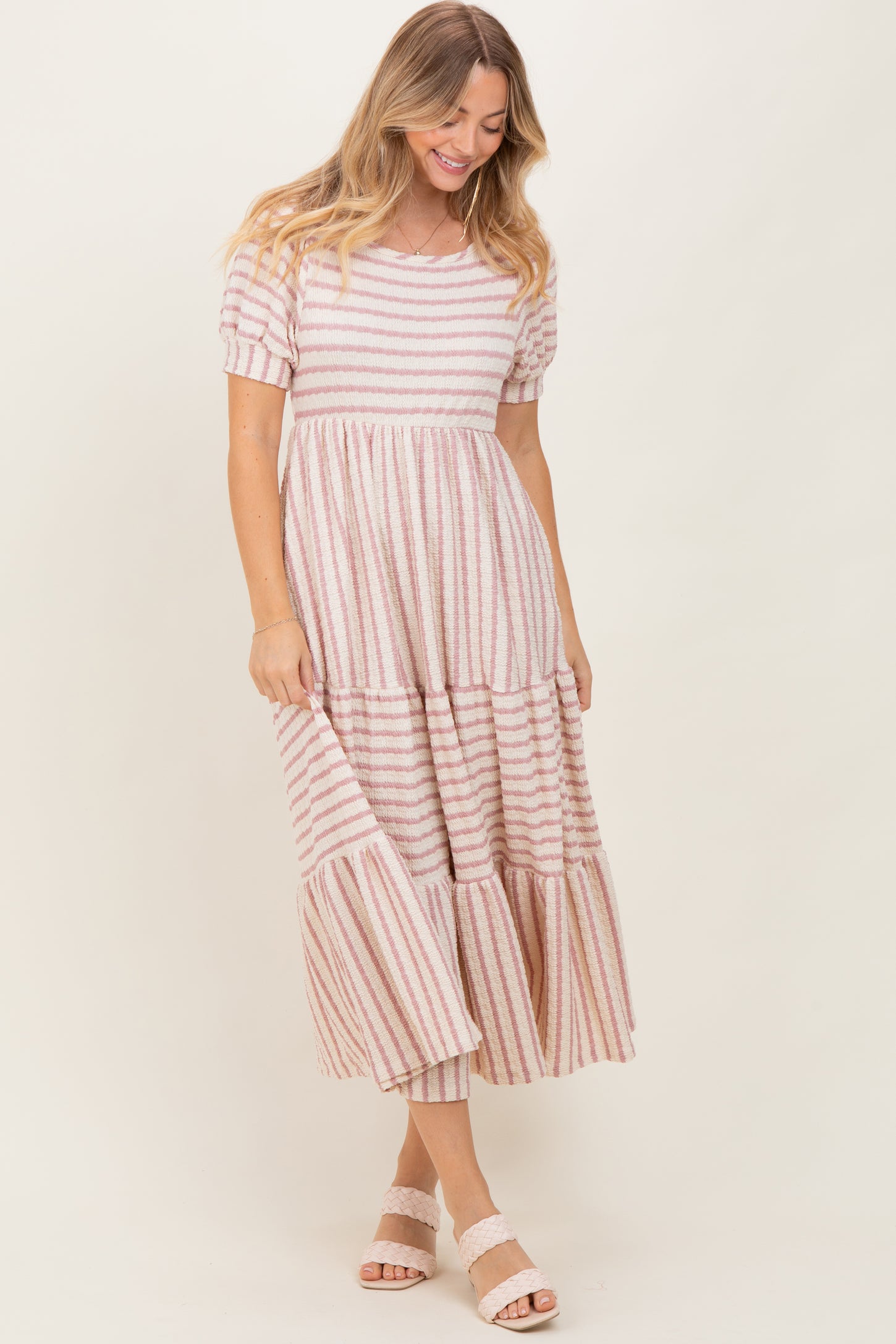 woman wearing a striped pink and white tiered maxi dress with short puff sleeves and a relaxed fit