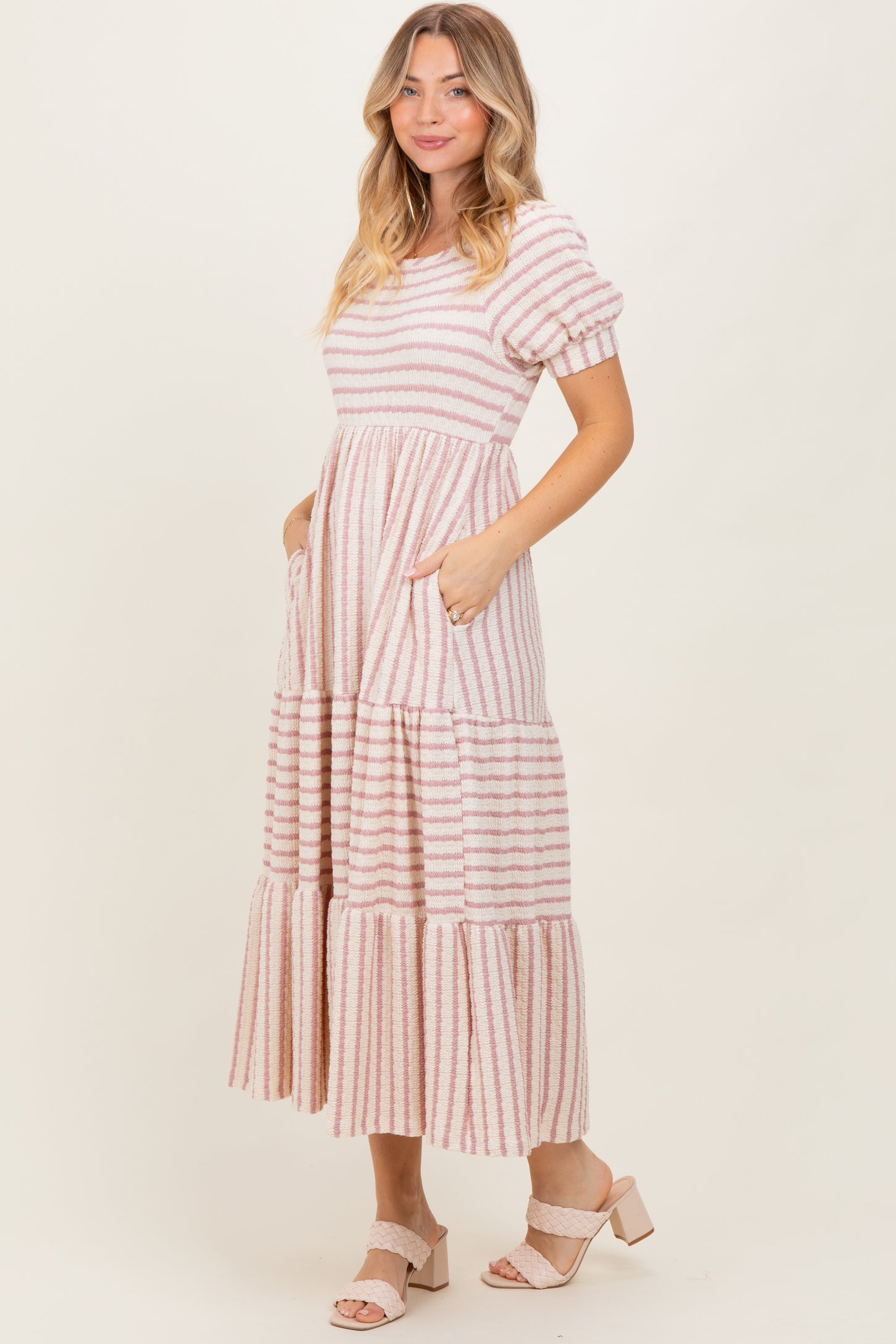 woman wearing a pink and white striped maxi dress with puff sleeves and pockets