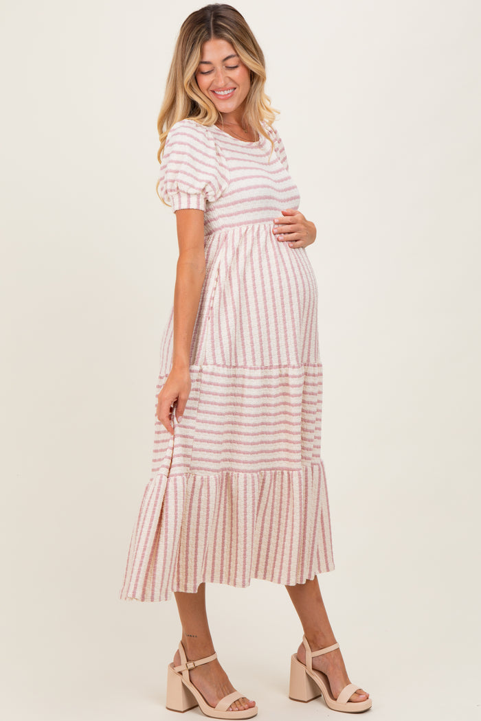 woman wearing a pink and white striped maternity dress with tiered skirt and a visible baby bump