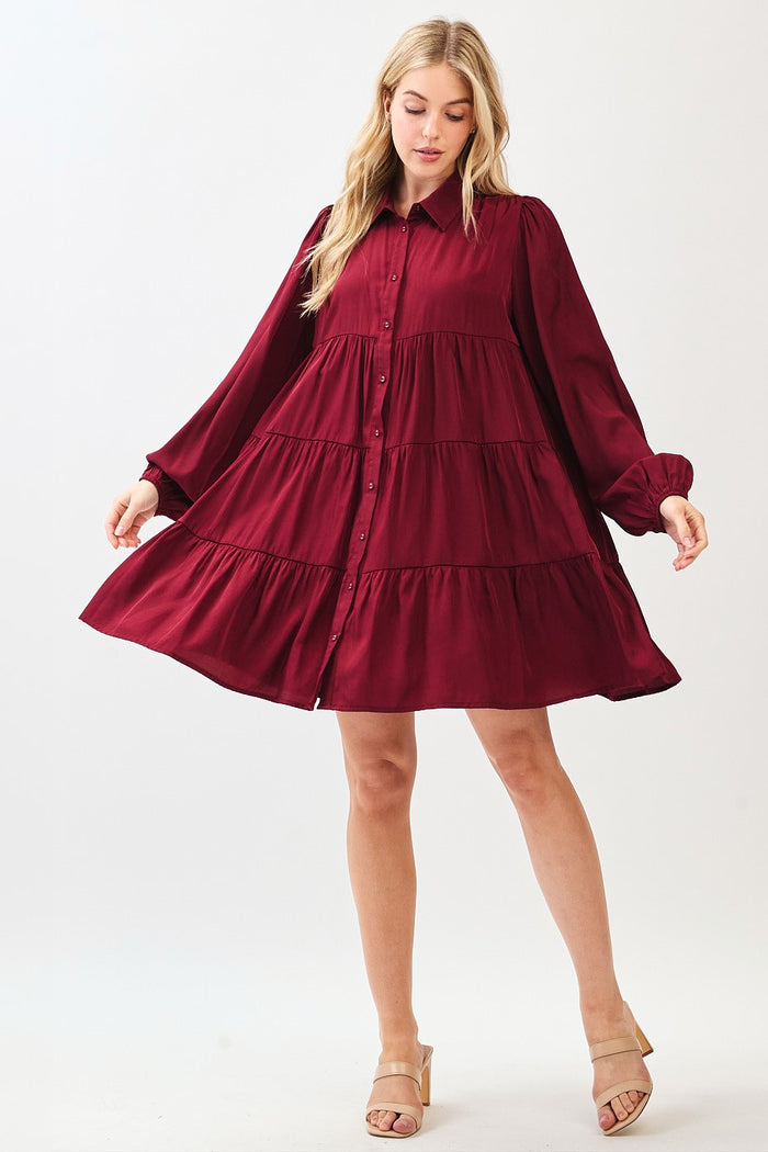 woman wearing a burgundy button-up tiered dress with long sleeves and a flowy silhouette