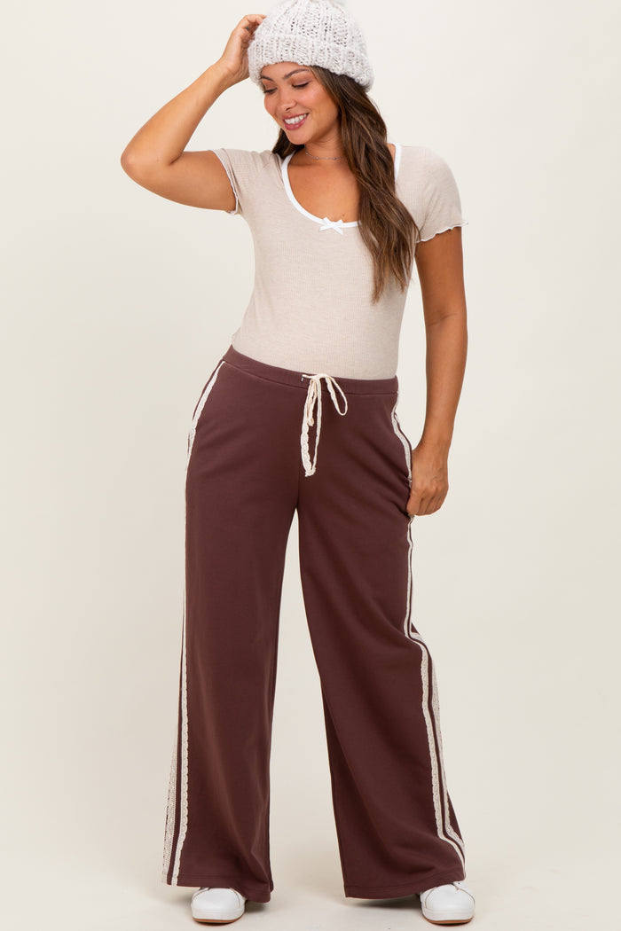 woman wearing a beige short sleeve maternity top and brown wide-leg maternity sweatpants with side stripes