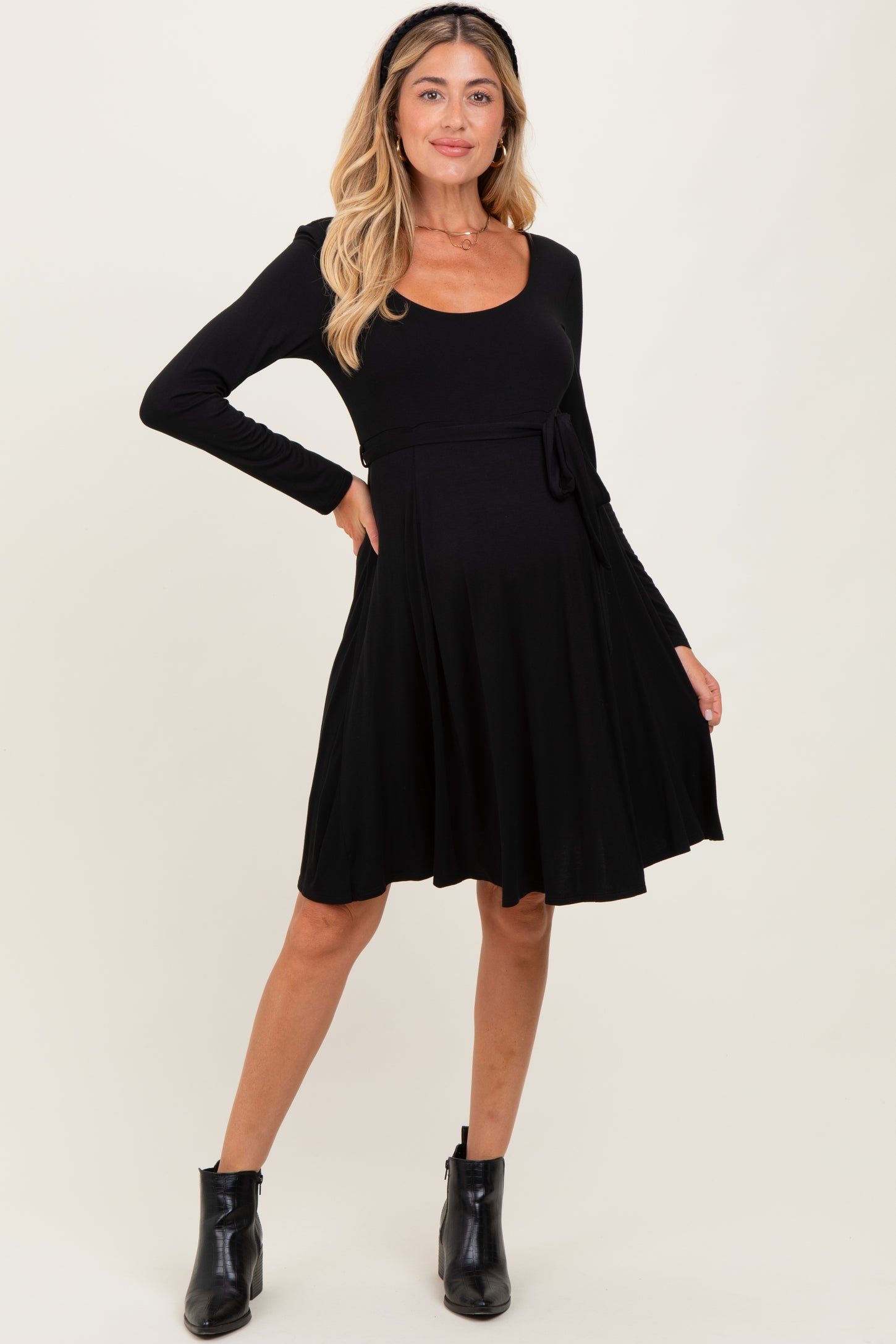 woman wearing a black long sleeve maternity dress with a tie at the waist and a visible baby bump