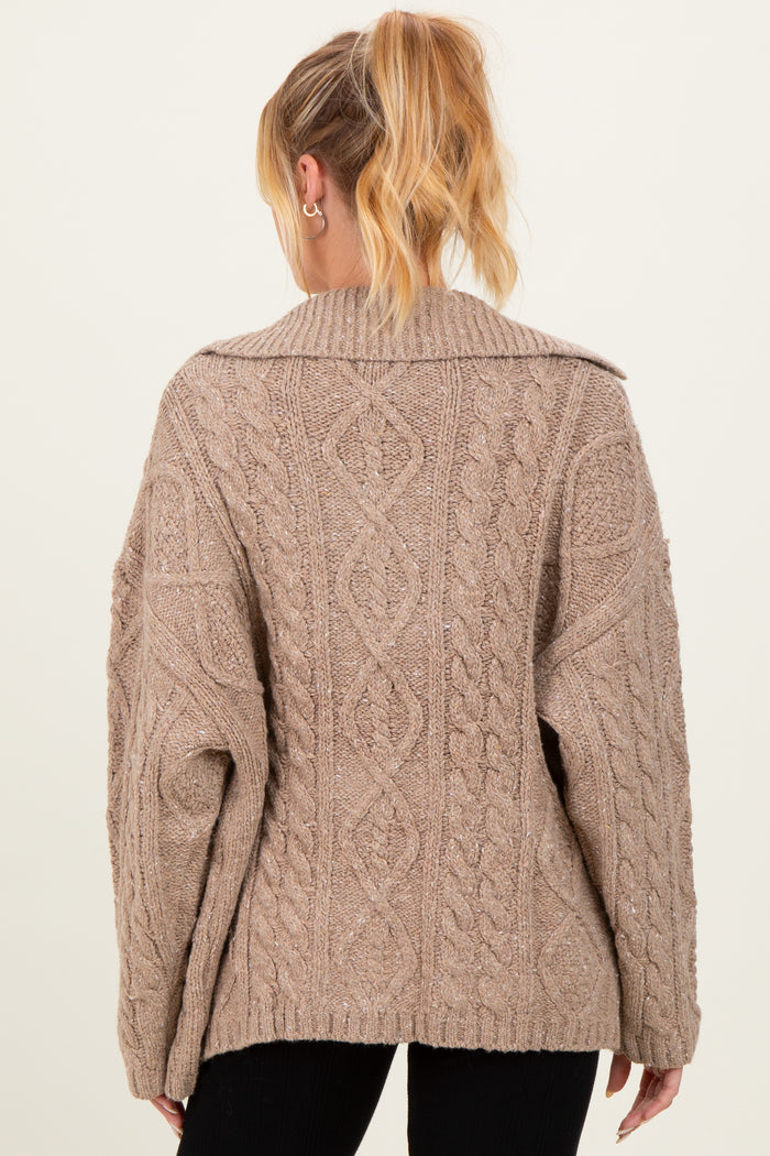 woman wearing a beige oversized cable knit maternity sweater viewed from the back